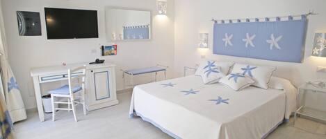 Un dormitorio con cama, escritorio, silla, televisión y baño.