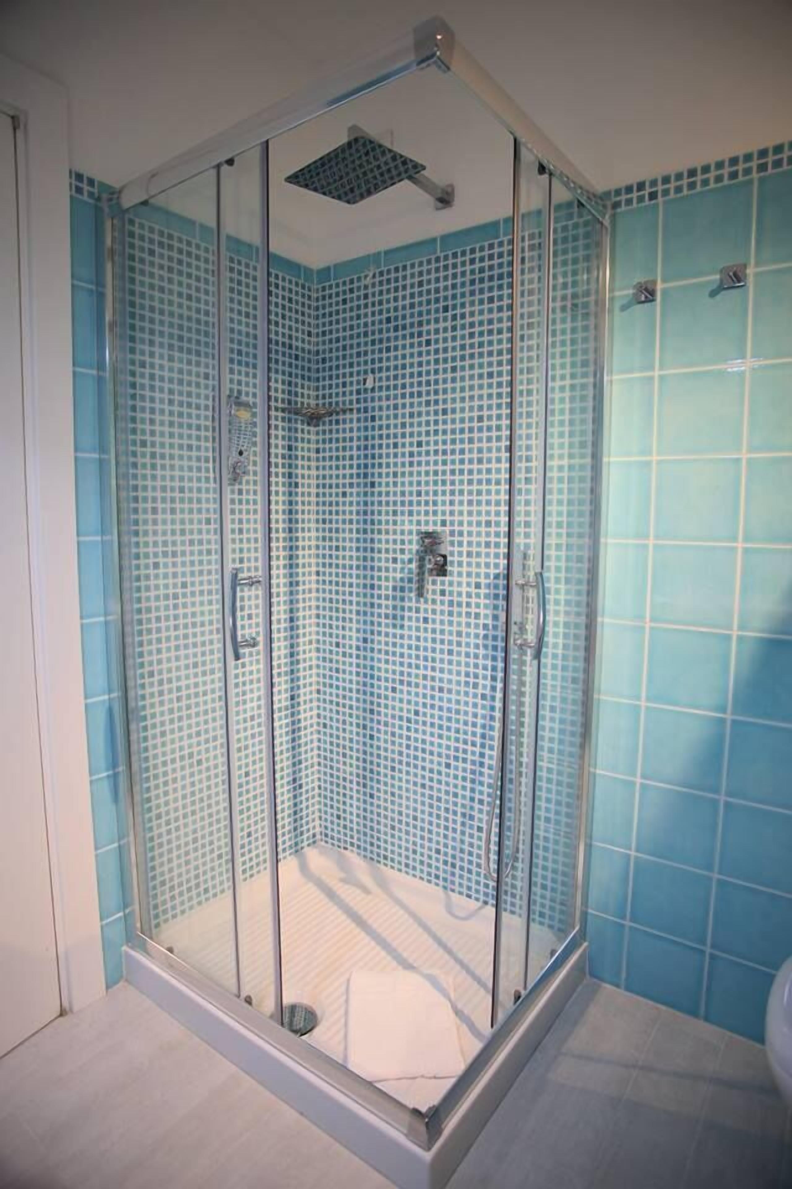 A glass-enclosed shower with a tiled wall and floor.
