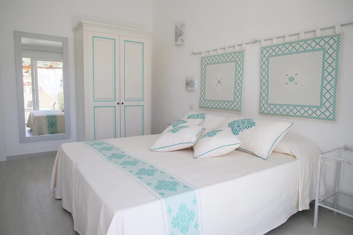 A bedroom with a bed, a wardrobe, and two wall-mounted quilts.