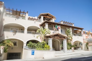 Un hôtel à plusieurs étages, doté de balcons, d’une entrée principale et d’un panneau indiquant l’emplacement du parking.