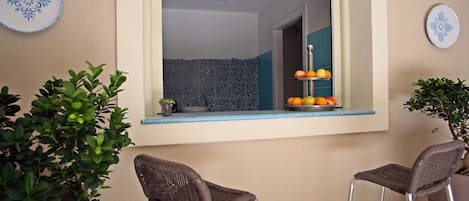A kitchen with a window, two wicker chairs, and a fruit basket.