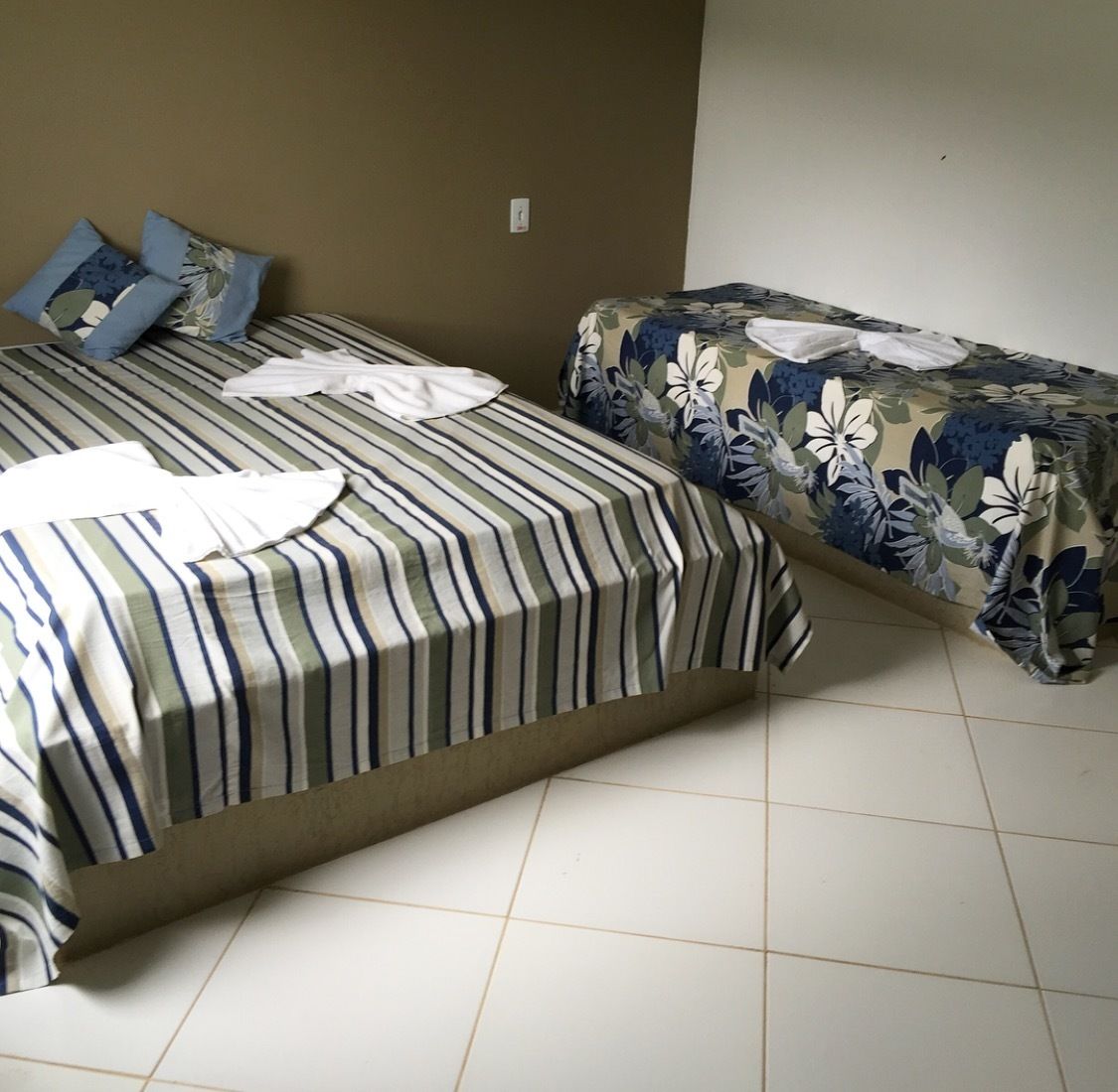 Una habitación con dos camas, una con ropa de cama a rayas y otra con estampado floral.