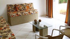 Una sala de estar con un sofá, una mesa de centro de vidrio y sillas de mimbre.
