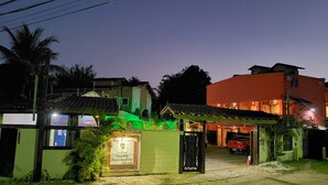 A building with a green entrance gate, a signboard, and a red car parked in front. - Pousada Parcel das Ilhas (São Sebastião)
