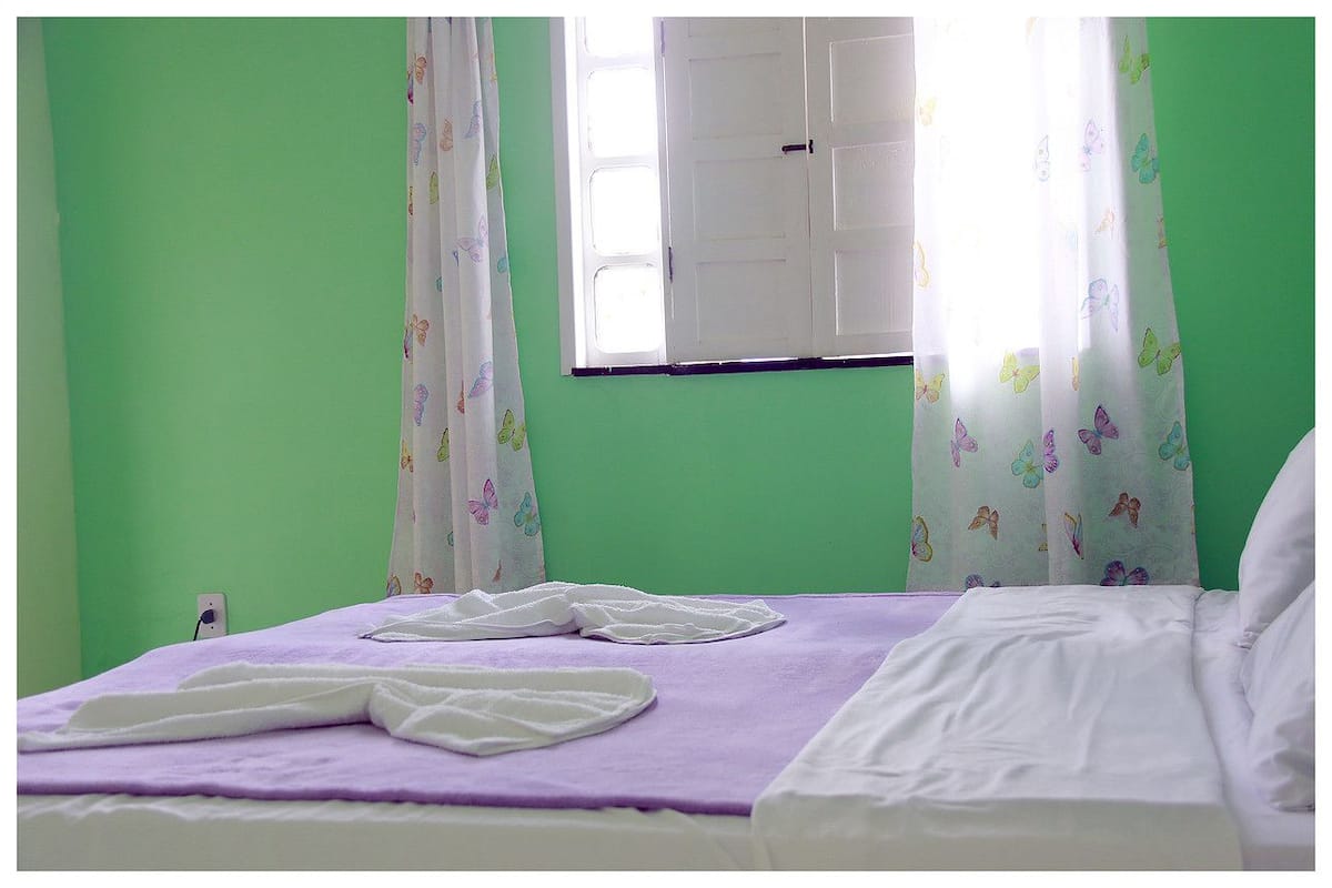 Een kamer met een bed, groene wanden en gordijnen met een vlindermotief.