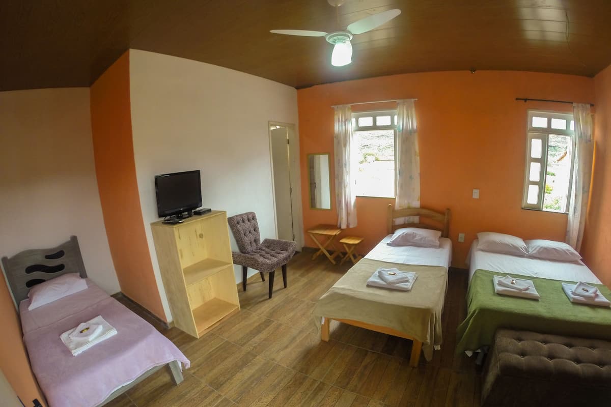 Een hotelkamer met twee enkele bedden, een houten garderobe, een televisie, een stoel en een bureau.