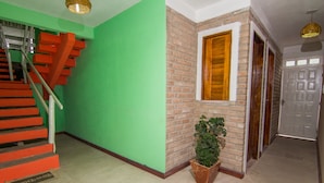 Eine Treppe mit roten Stufen, eine grüne Wand, eine Backsteinmauer mit einem Fenster und ein Blumentopf.