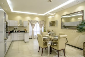 A modern kitchen with white cabinets, a dining area with a marble table and four chairs, and a large mirror on the wall. - The Landmark Suites Westlands, Nairobi- Next to Westgate Mall (Nairobi)