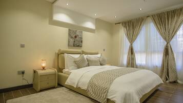 A bedroom with a bed, nightstand, lamp, and a painting on the wall.
