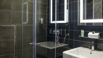 A modern bathroom with a glass-enclosed shower, a white sink, and a large mirror.