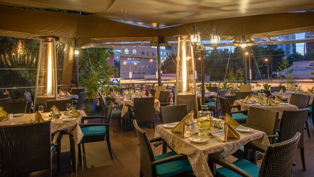 An outdoor restaurant with tables set for dining, surrounded by wicker chairs and covered by a canopy. - The Landmark Suites Westlands, Nairobi- Next to Westgate Mall (Nairobi)