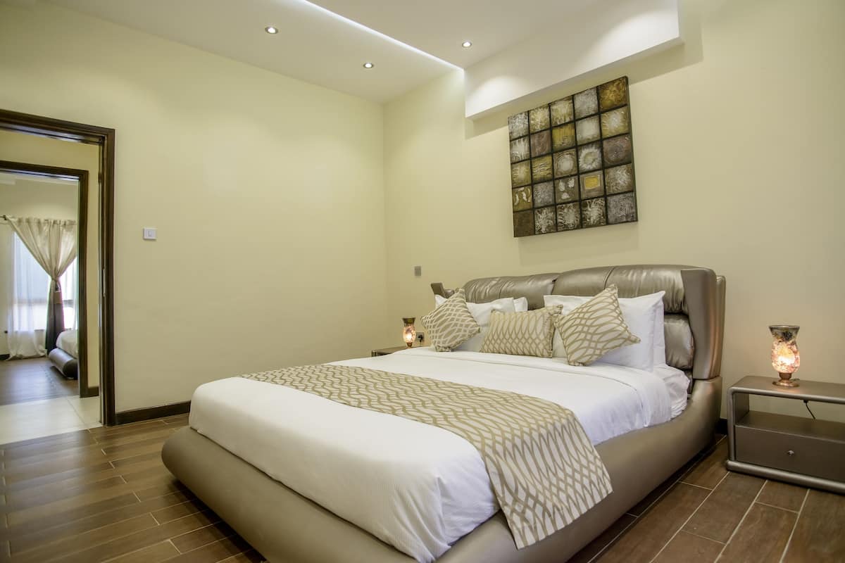A modern bedroom with a large bed, a nightstand, and a wall art piece.