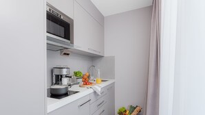 A compact kitchen with a microwave, coffee machine, and a sink. There is a basket with vegetables and bread on the counter. - VISIONAPARTMENTS Lucerne Neustadtstrasse (Lucerne)