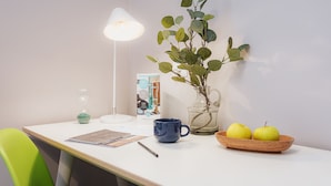 A table with a lamp, a vase with green leaves, a blue mug, a bowl with apples, and a green chair. - VISIONAPARTMENTS Lucerne Neustadtstrasse (Lucerne)