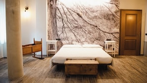 A bedroom with a large bed, wooden bench, nightstands, and a marble wall mural. - Hotel Rendez Vous (Chatillon)