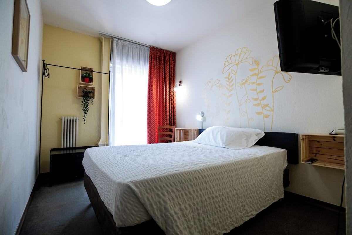 Un dormitorio con una cama, un escritorio, una silla, un radiador y una pared con diseño floral.
