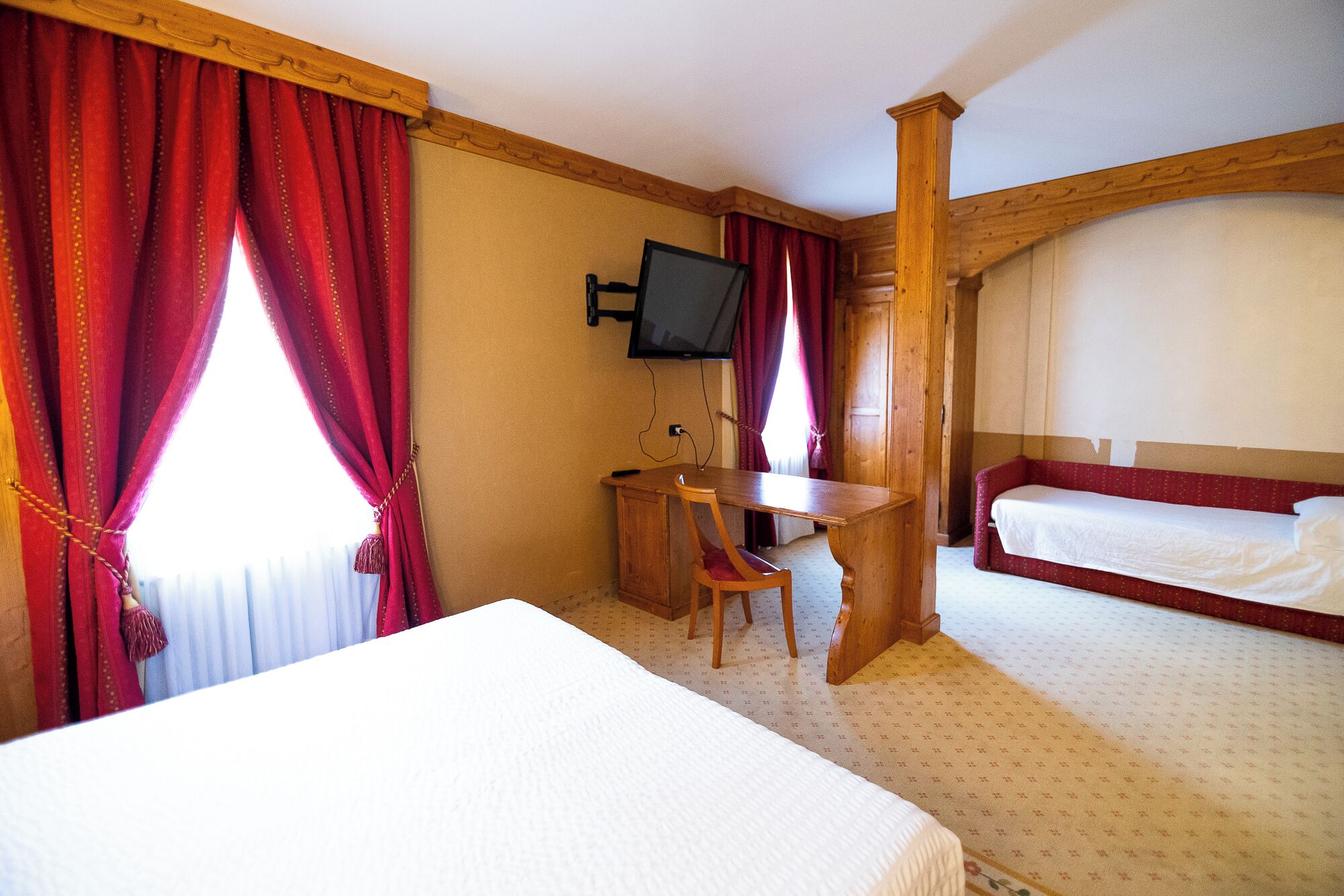 A hotel room with a bed, a desk, and a TV.