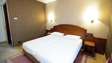 Une chambre d’hôtel avec un grand lit, deux tables de chevet et deux lampes fixées au mur.
