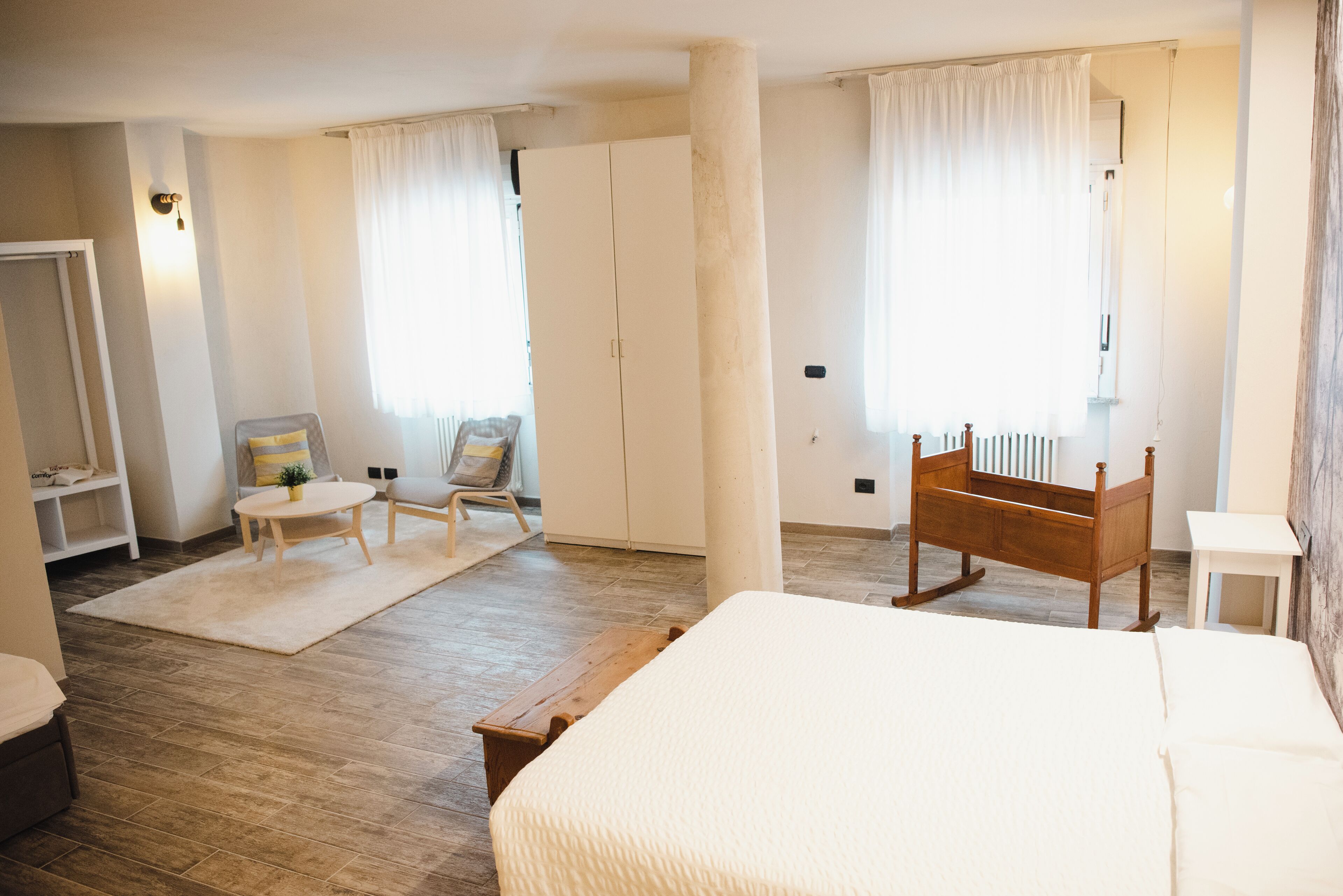 Ein Schlafzimmer mit einem großen Bett, einem hölzernen Schaukelstuhl, einem kleinen Tisch und einem Kleiderschrank.