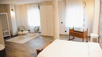 A bedroom with a large bed, a wooden rocking chair, a small table, and a wardrobe.