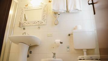 Ein Badezimmer mit einem Standwaschbecken, einer Toilette und einem Spiegel mit dekorativen Rahmen.