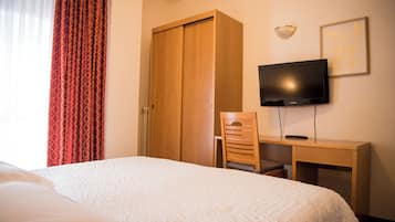 Une chambre d’hôtel équipée d’un lit, d’un bureau, d’une chaise, d’une télévision et d’une armoire.