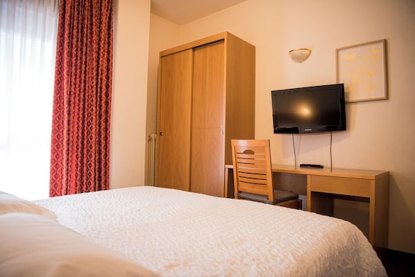 A hotel room with a bed, a desk, a chair, a television, and a wardrobe. - Hotel Rendez Vous (Chatillon)