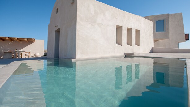 Un edifici modern amb piscina, amb un disseny arquitectònic únic, grans finestres i un cel blau i clar.
