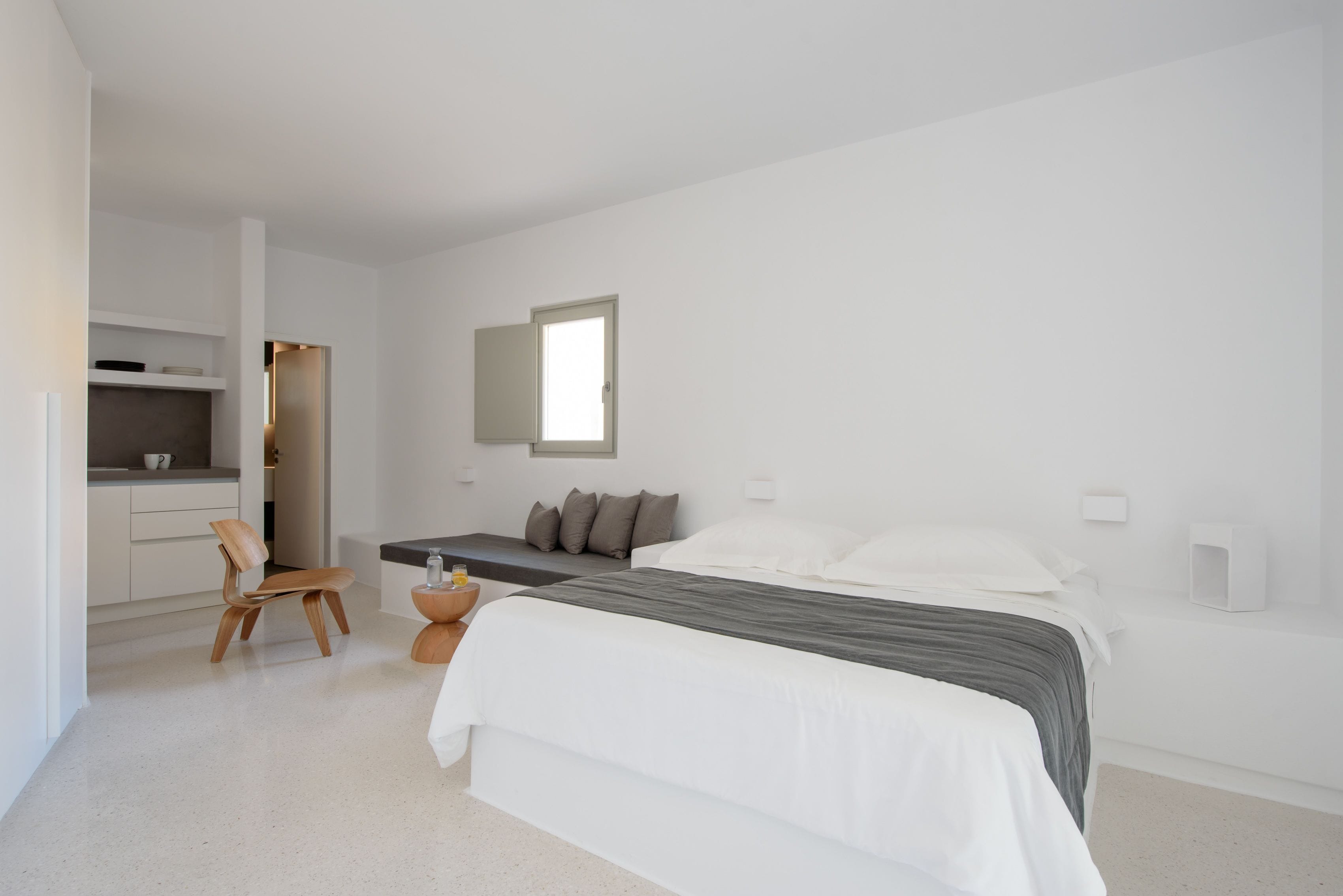 Une chambre à coucher au style minimaliste, avec un lit, une table de chevet et une chaise.