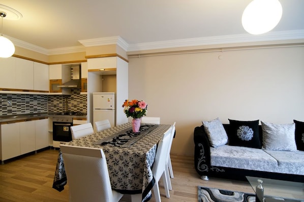 A modern kitchen with white cabinets, a tiled backsplash, and a dining area with a table set for two.