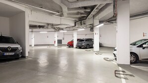 Een parkeergarage met diverse parkeerplaatsen, betonnen pilaren en verlichting aan het plafond.