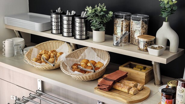 Een ontbijtbuffet met diverse etenswaren, manden en bakken.
