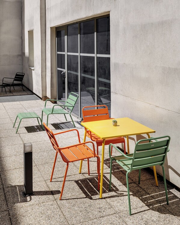 Un espace extérieur aménagé avec une table et des chaises, une fenêtre et un mur en béton.