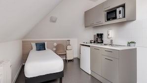 Een knus verblijf met een bed, kitchenette en een zithoekje.