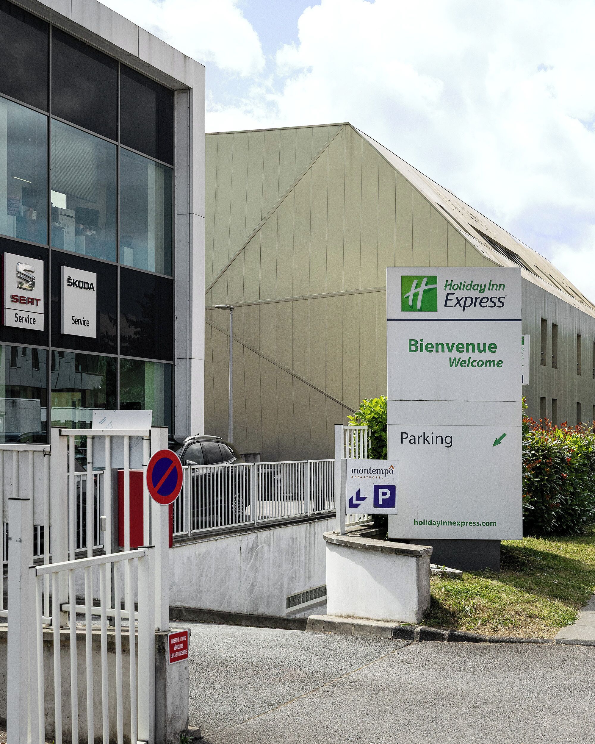 A Holiday Inn Express sign, a parking sign, and a service sign for SEAT and ŠKODA.