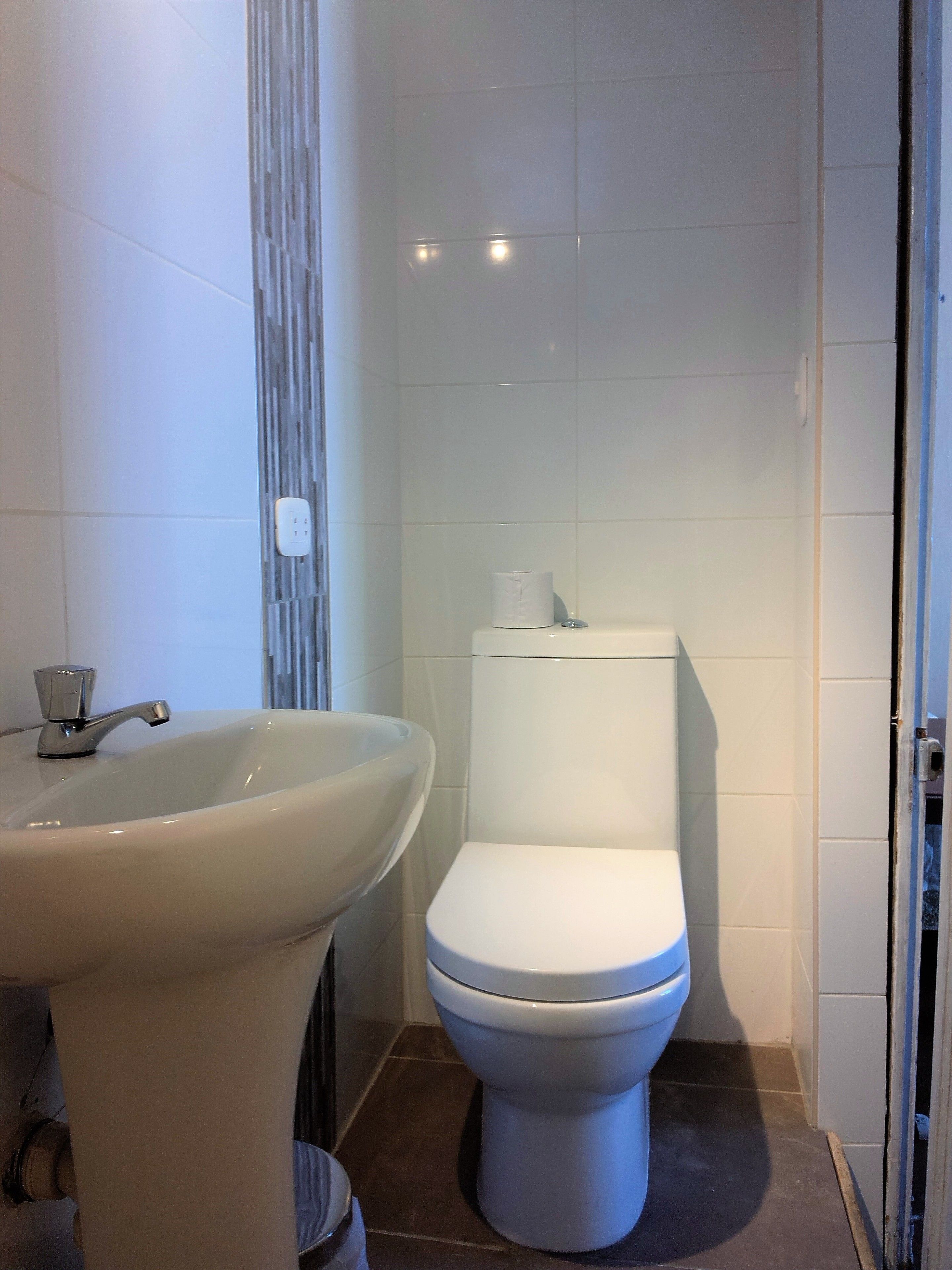 A bathroom with a white sink, toilet, and tiled walls.