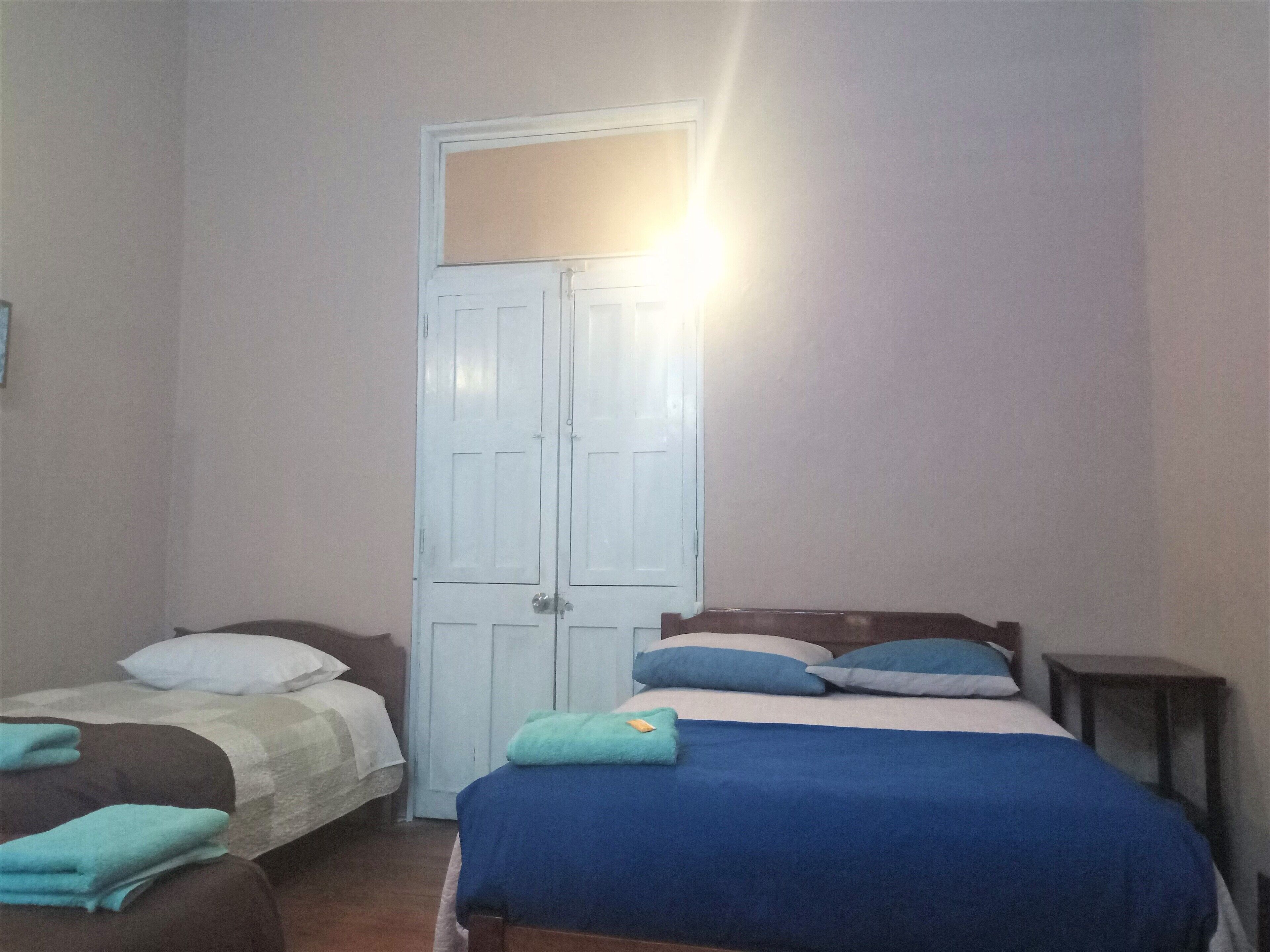 A bedroom with two beds, a wardrobe, and a bedside table.