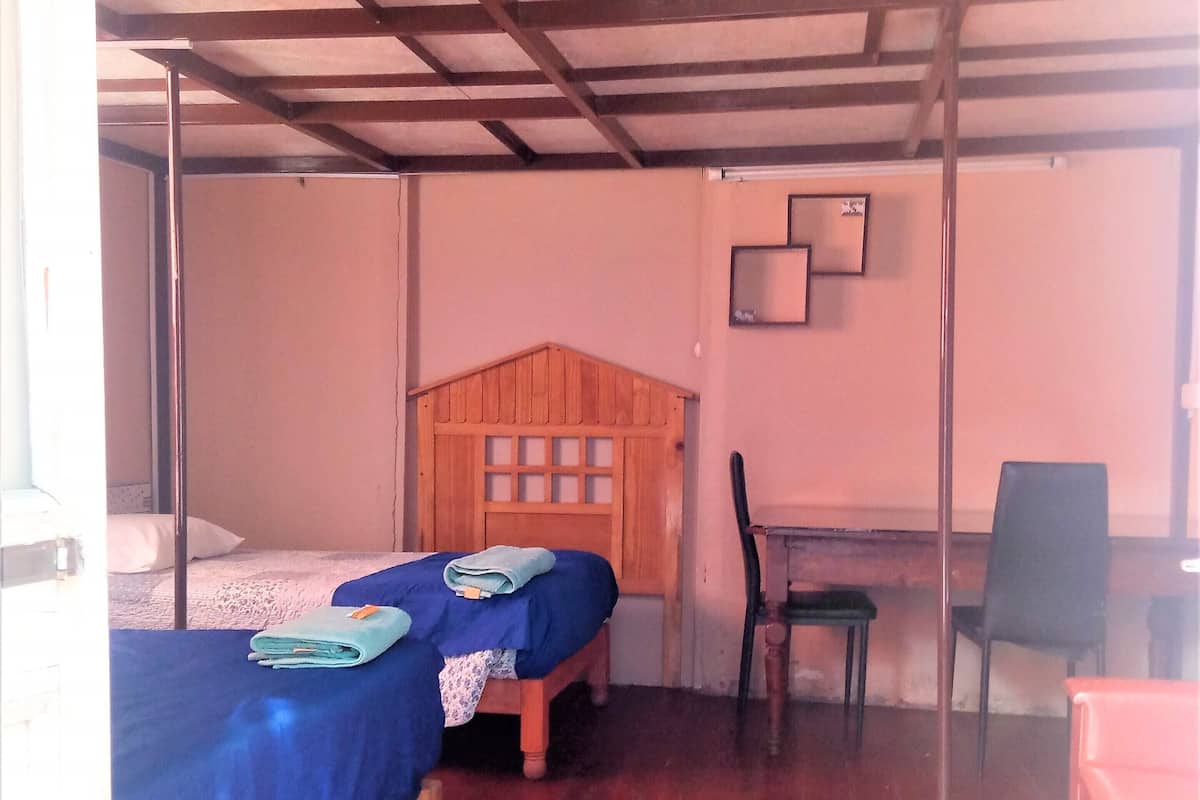 A room with two wooden beds, a desk with a chair, and a wooden partition wall.