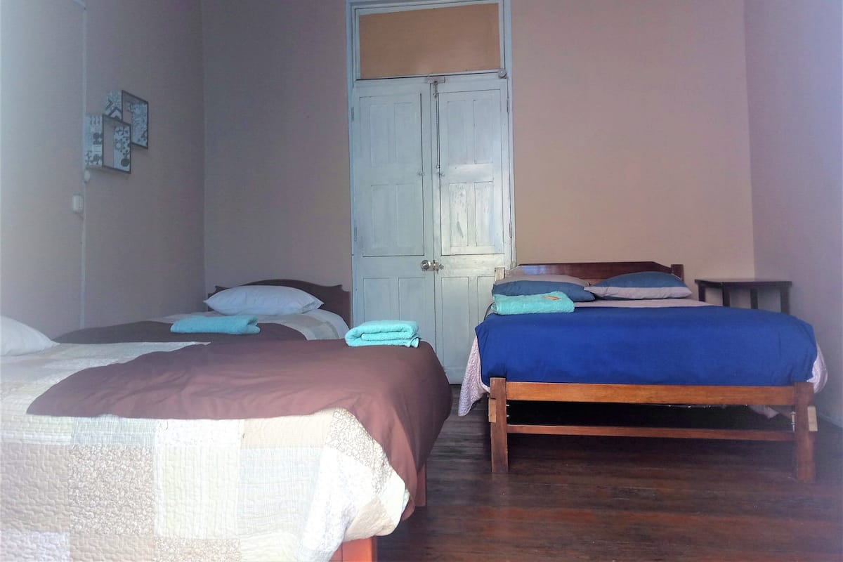 A bedroom with two beds, a wardrobe, and a small table.
