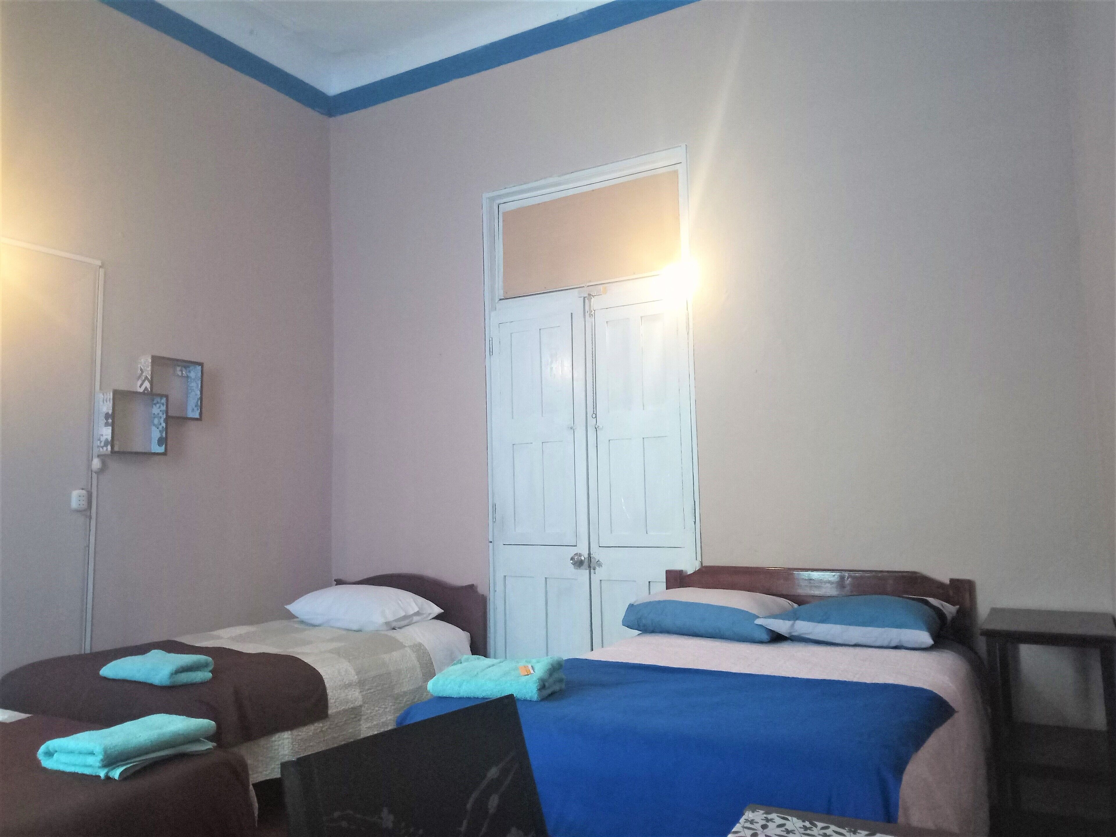 A bedroom with two beds, a wardrobe, and a small table.