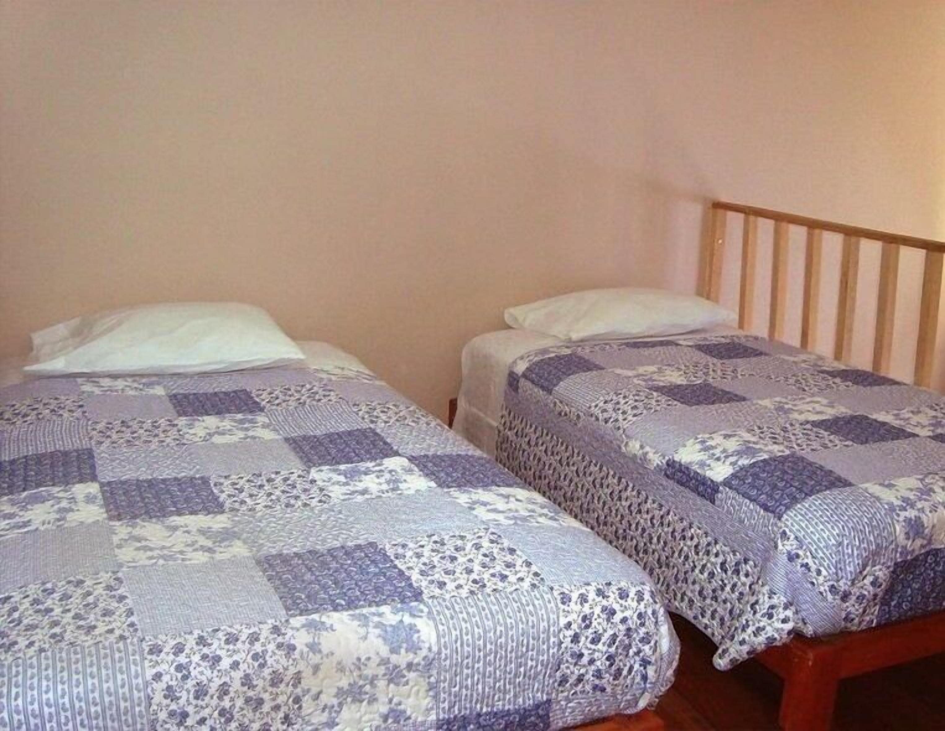 Two single beds with wooden headboards, each with a patterned bedspread.
