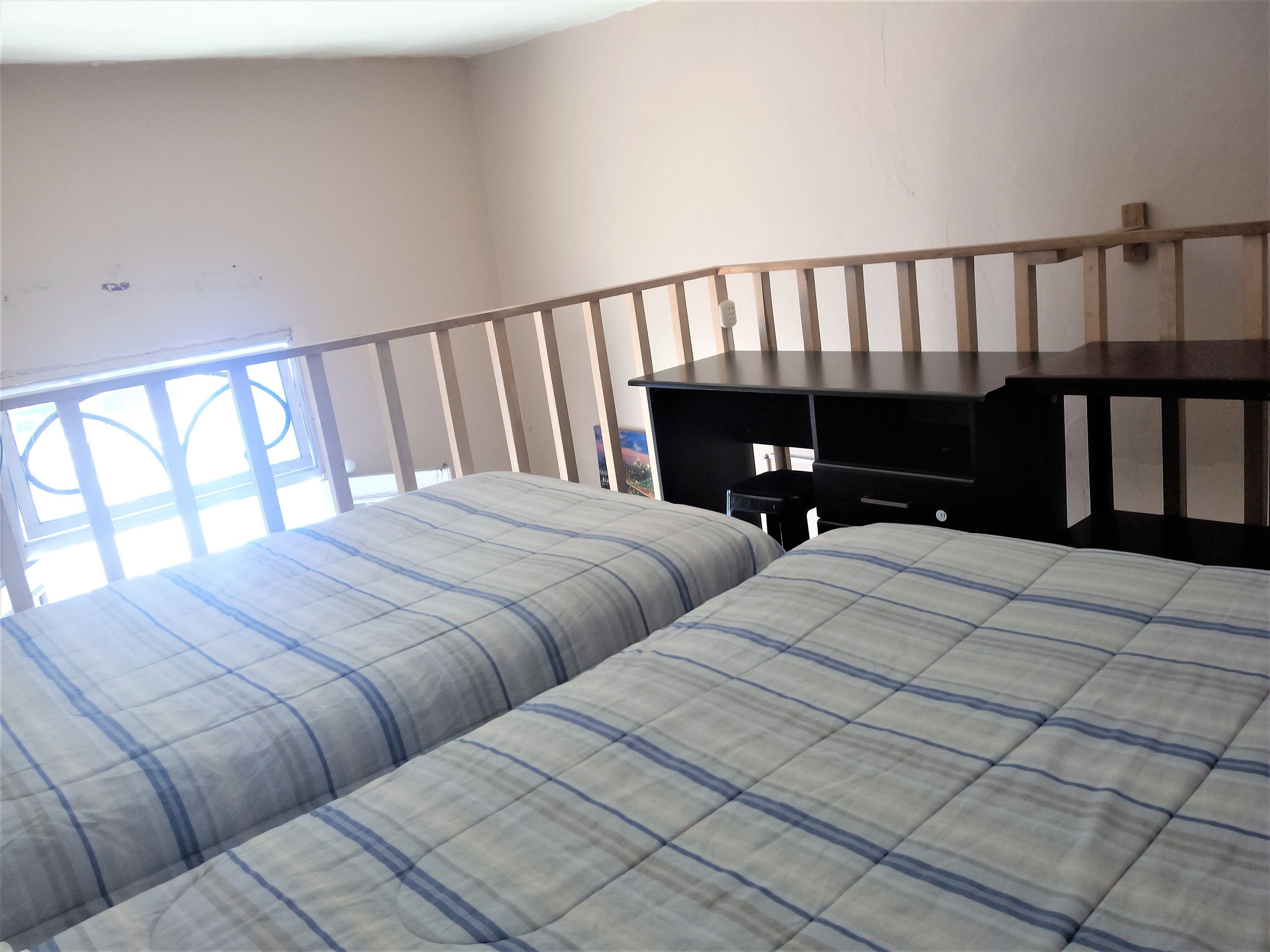 Une chambre avec deux lits, un bureau et une fenêtre.