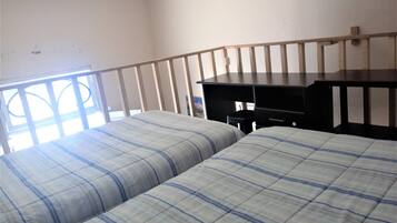 Ein Zimmer mit zwei Betten, einem Schreibtisch und einem Fenster.