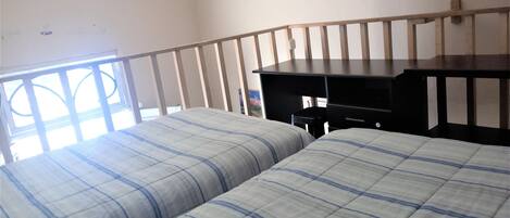 A room with two beds, a desk, and a window.