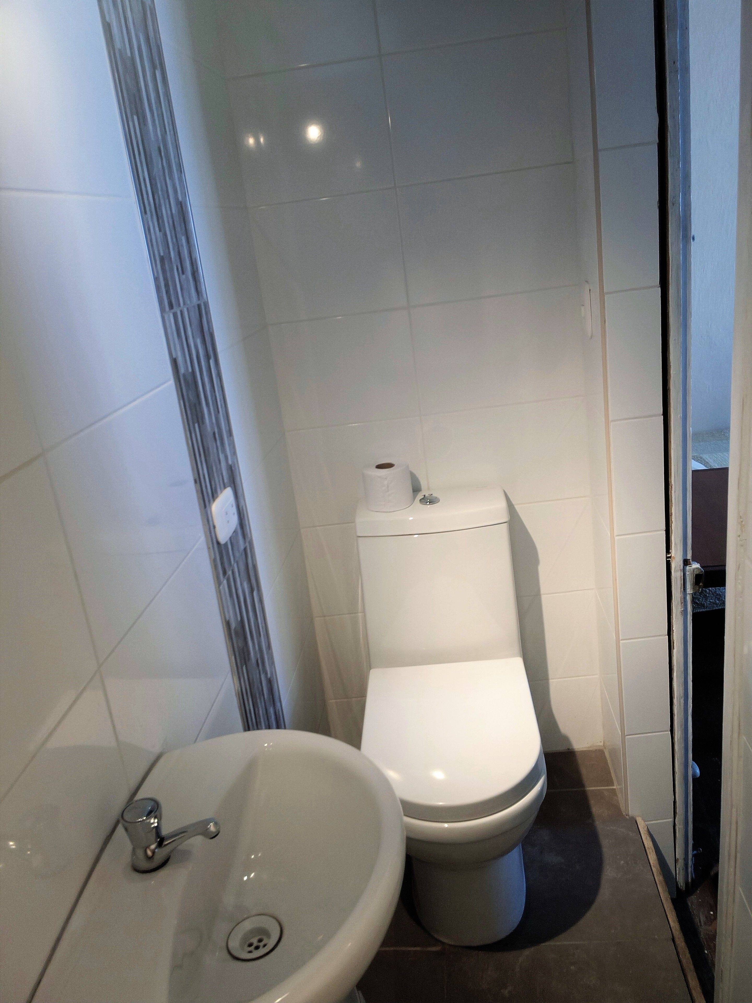 A small, modern bathroom with a toilet, a sink, and a shower area.