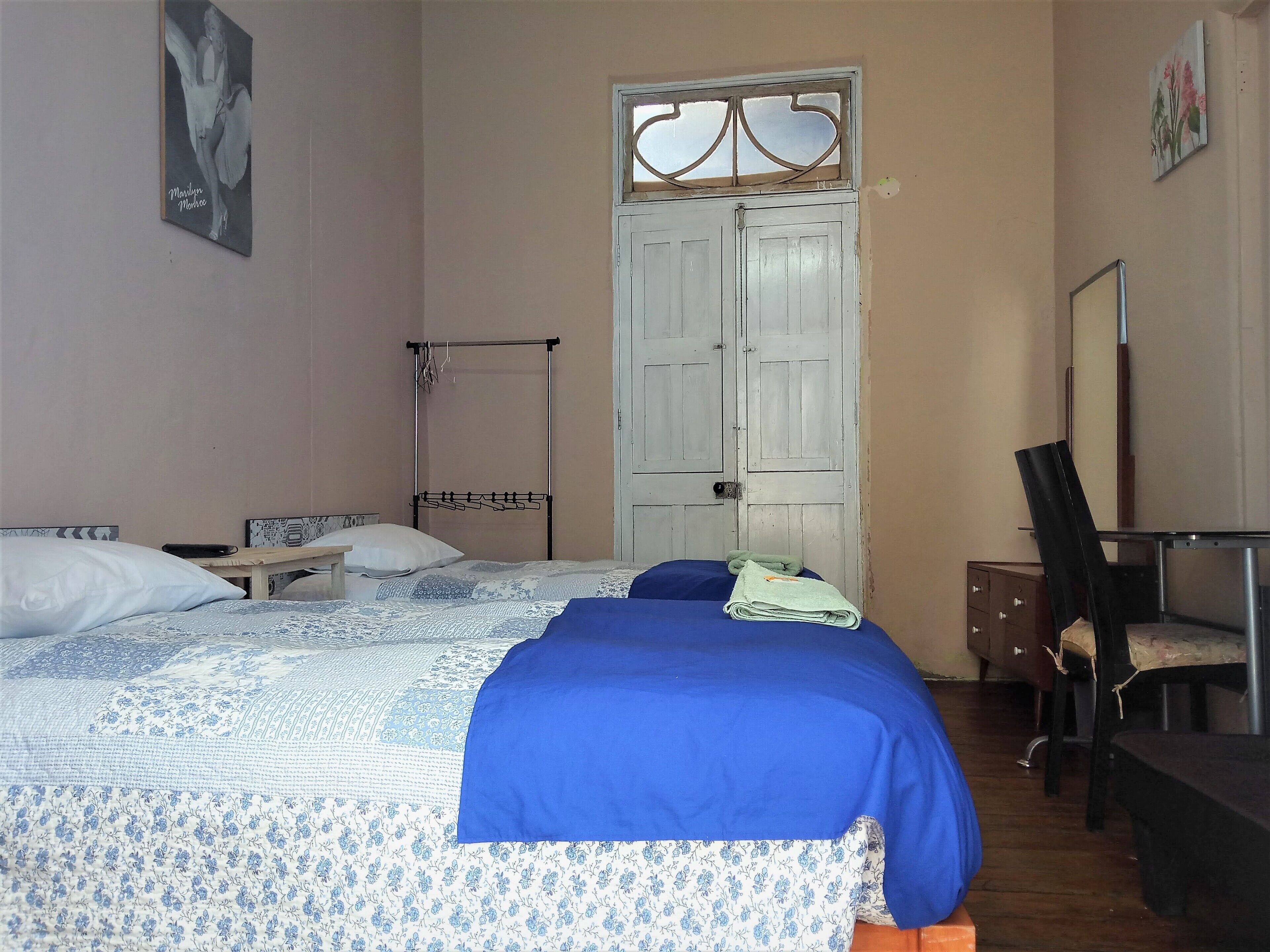A bedroom with a bed, a desk, and a wardrobe.