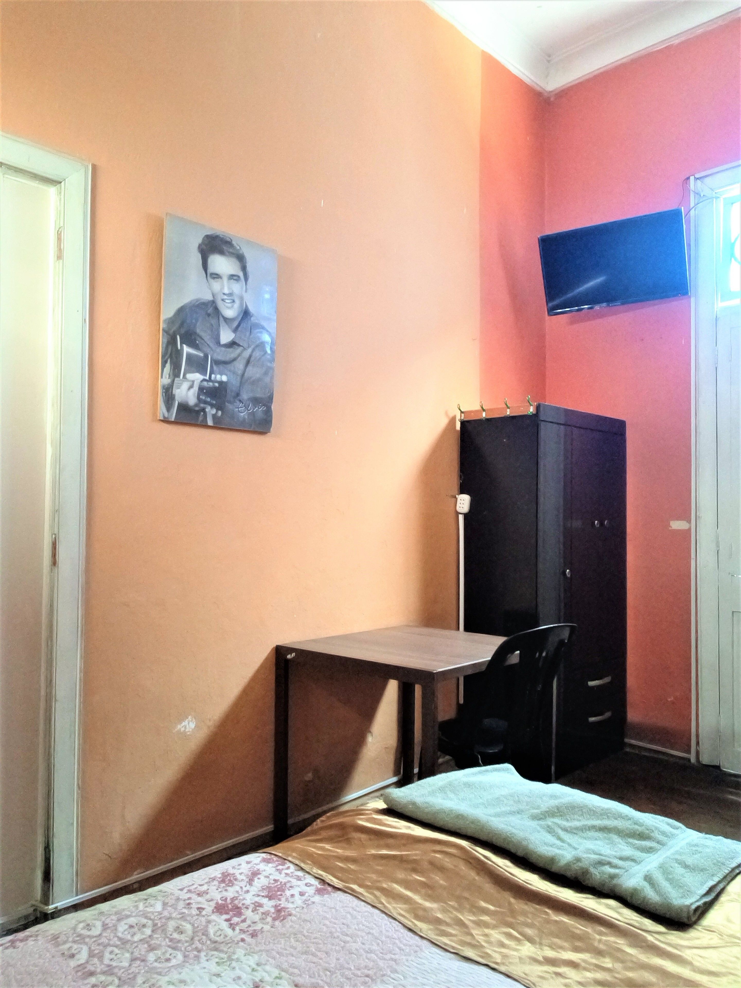 A small room with a bed, a desk, and a wardrobe.