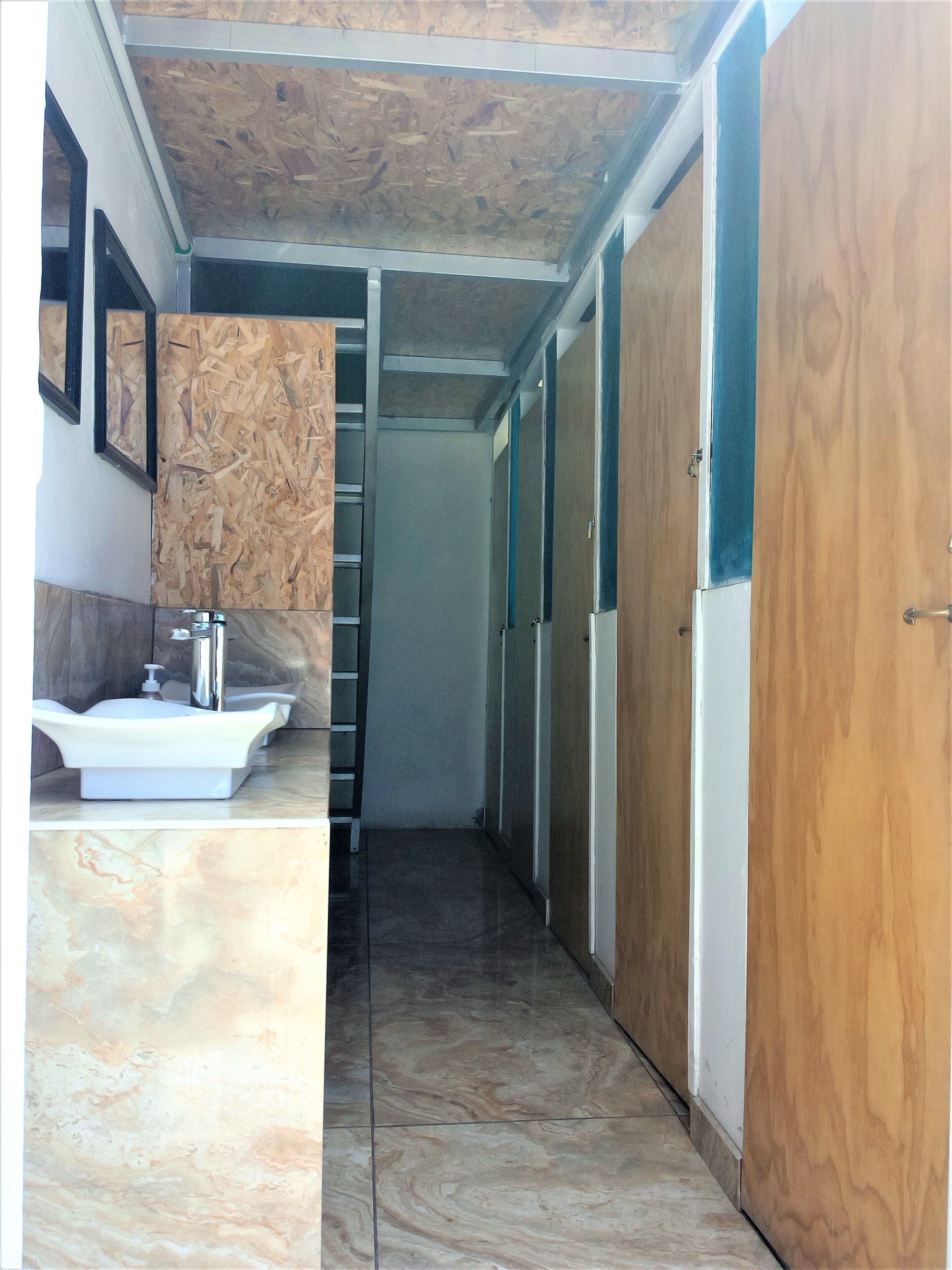 A narrow hallway with a bathroom on the left, featuring a sink and mirror.