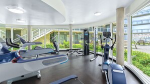 Un gimnasio con cintas de correr, elípticas y equipo de pesas.