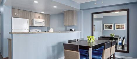 A modern kitchen with a built-in microwave, a refrigerator, and a ceiling fan.